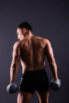 Shirtless bodybuilder showing his great body and holding dumbells.