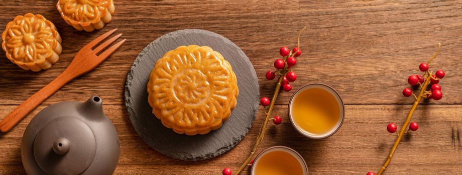 Moon cake Mooncake table setting - Chinese traditional pastry with tea cups on wooden background, Mid-Autumn Festival concept, top view, flat lay.