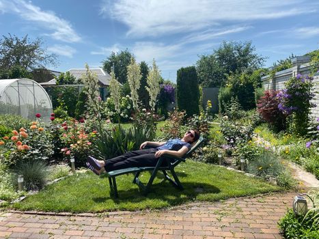 Woman relaxing on a garden recliner chair in Backyard of house