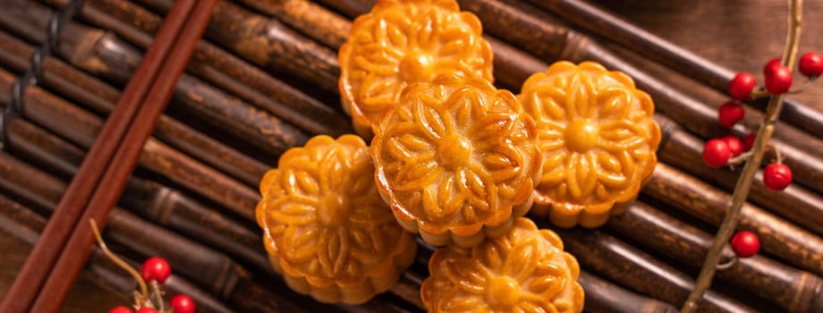 Chinese traditional pastry Moon cake Mooncake with tea cups on bamboo serving tray on wooden background for Mid-Autumn Festival, top view, flat lay.