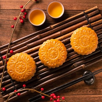 Chinese traditional pastry Moon cake Mooncake with tea cups on bamboo serving tray on wooden background for Mid-Autumn Festival, top view, flat lay.