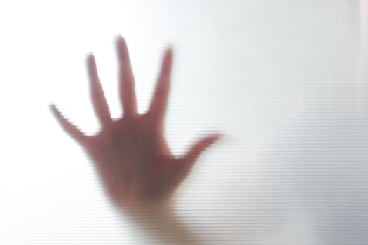 Diffused silhouette of female hands through frosted glass