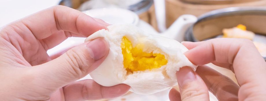 Delicious dim sum, famous cantonese food in asia, fresh and hot salted creamy custard buns in bamboo steamer in hong kong yumcha restaurant, close up