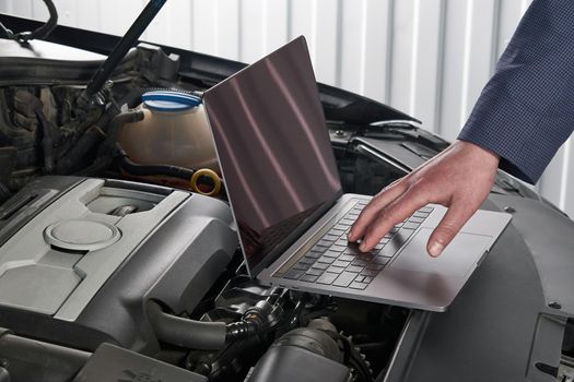 Services car engine machine concept, Automobile mechanic repairman checking a car engine with using computer diagnostics while repairing, car service and maintenance.