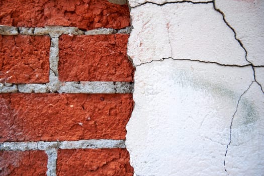 Old red brick wall with peeled off plaster close-up