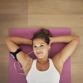 I have every reason to be happy. High angle shot of a young woman listening to music while lying on her yoga mat