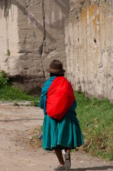 poor indian old woman walking on a sandy mountain with traditional hat. High quality photo