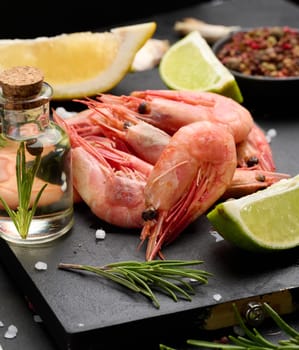 Boiled shrimp on a board, lemon slices, spices on a black background