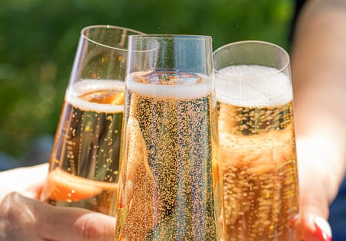 women drinking wine. three glasses white wine in female hands. flute glass of champagne with bubbles outdoors isolated against. garden scene blurred in the background. Cold Beer in glass. outdoor