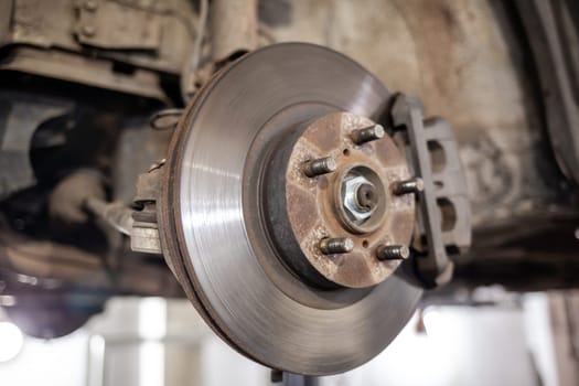 Disc brake of the vehicle for repair, in process of new tire replacement. Car brake repairing in garage.Suspension of car for maintenance brakes and shock absorber systems. Replacement of brake pads.