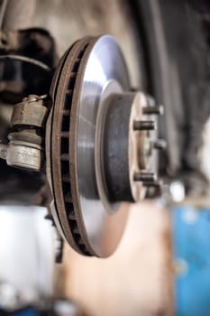 Disc brake of the vehicle for repair, in process of new tire replacement. Car brake repairing in garage.Suspension of car for maintenance brakes and shock absorber systems. Replacement of brake pads.