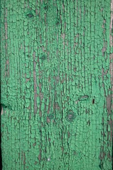 Wood texture with green flaked paint. Peeling paint on weathered wood. Old cracked paint pattern on rusty background. Chapped paint on an old wooden surface