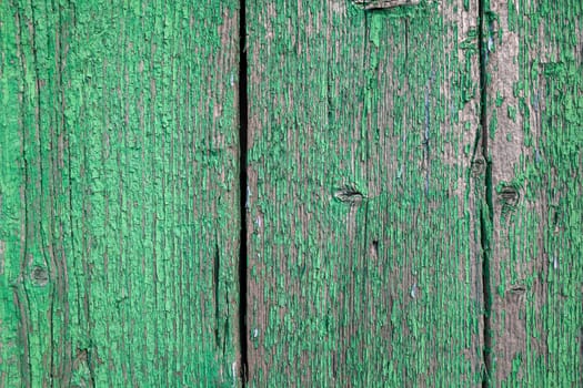Wood texture with green flaked paint. Peeling paint on weathered wood. Old cracked paint pattern on rusty background. Chapped paint on an old wooden surface