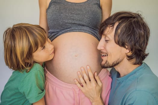 Father and elder son listen to mom's pregnant belly.