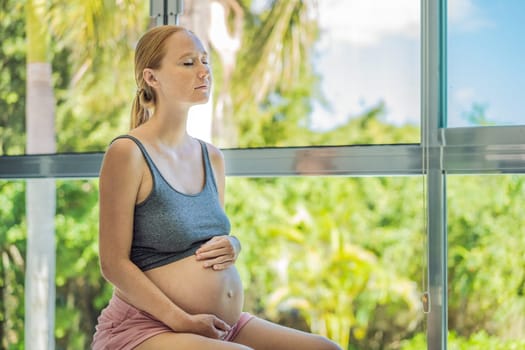 Pregnant woman exercising on fitball at home. Pregnant woman doing relax exercises with a fitness pilates ball. Against the background of the window.