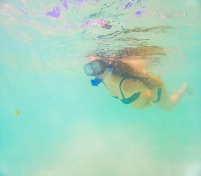 Pregnant woman underwater swimming in tropical sea. Healthy and active pregnancy. Young expecting mom on summer beach vacation before baby birth. Swim holiday and water fun. Travel during pregnancy. Underwater photography.