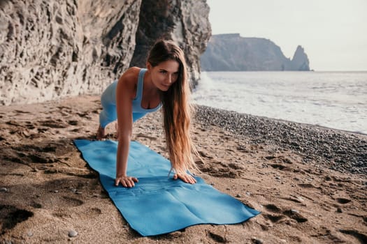 Middle aged well looking woman with black hair doing Pilates with the ring on the yoga mat near the sea on the pebble beach. Female fitness yoga concept. Healthy lifestyle, harmony and meditation.