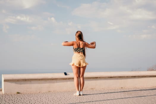 silhouette of a happy woman who dances, spins and raises her hands to the sky. A woman is enjoying a beautiful summer day.