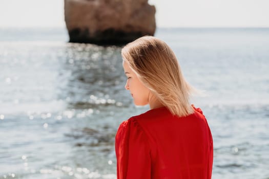 Woman travel sea. Young Happy woman in a long red dress posing on a beach near the sea on background of volcanic rocks, like in Iceland, sharing travel adventure journey