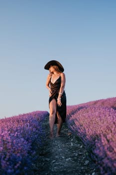 Close up portrait of young beautiful woman in a white dress and a hat is walking in the lavender field and smelling lavender bouquet.