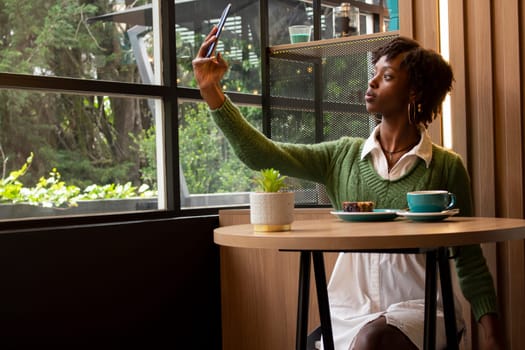 Afro woman taking a selfie in a restaurant in the city while having a coffee. High quality photo