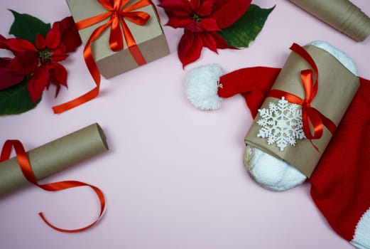 The concept of Christmas. On a pink background, Christmas gifts are laid out, gift wrapping, Santa's hat, freshly prepared stollen and Poinsettia flower are laid out.