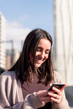 young woman smiling happy while using her mobile phone, concept of modern lifestyle and technology of communication, copy space for text
