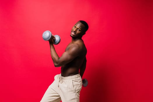 Portrait of happy african man with dumbbells over red and black background