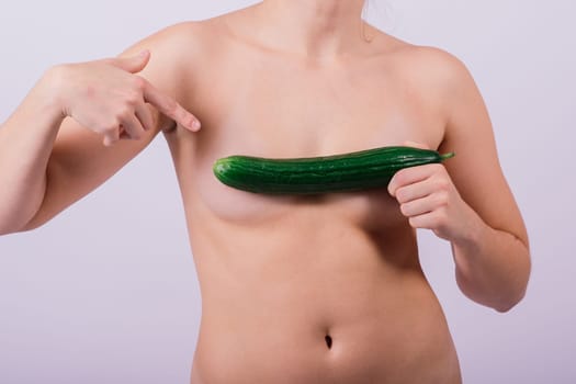 Close up portrait of an attractive young woman topless with cucumber in studio