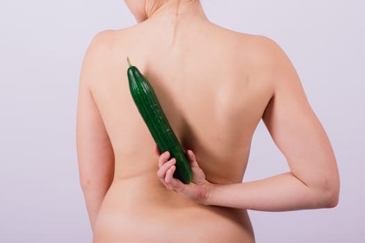 Close up portrait of an attractive young woman topless with cucumber in studio