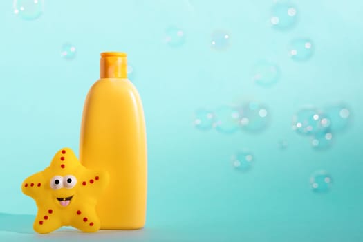 A mock up of a yellow bottle with cosmetic and bath accessories. Kid's shower gel with a place for logo