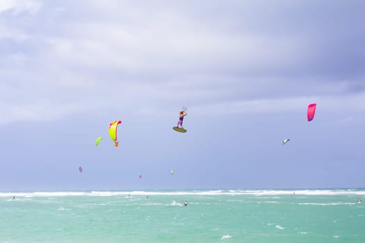 Kiteboarding. Fun in the ocean. Extreme Sport Kitesurfing. Kitesurfer jumping high in the air performing triks during kitesurfing session