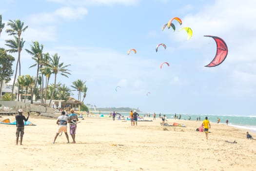 Crowd of active sporty people enjoying kitesurfing holidays and activities on perfect sunny day on Cabarete tropical sandy beach in Dominican Republic