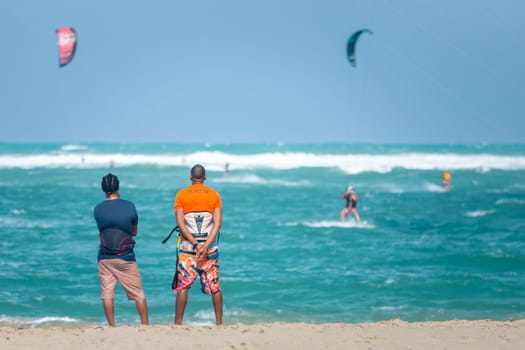 Active sporty people enjoying kitesurfing holidays and activities on perfect sunny day on Cabarete tropical sandy beach in Dominican Republic