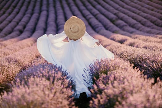 Happy woman in a white dress and straw hat strolling through a lavender field at sunrise, taking in the tranquil atmosphere