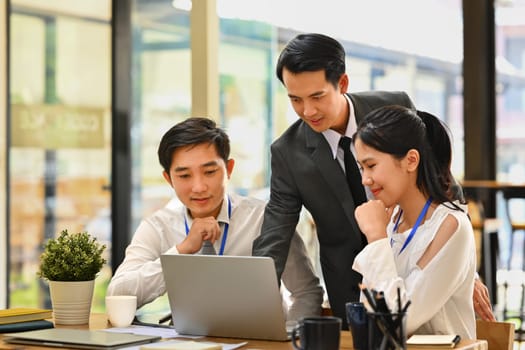 Business team looking at laptop monitor and discussing over new business project at office.