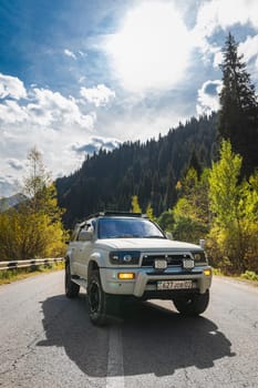 Japanese off-road used white 4x4 car Toyota 4runner on autumn mountain road trip, copy space, vertical. Almaty, Kazakhstan - September 28, 2022