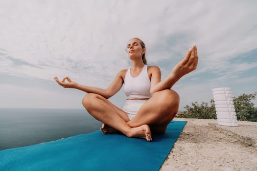 Middle aged well looking woman with black hair doing Pilates with the ring on the yoga mat near the sea on the pebble beach. Female fitness yoga concept. Healthy lifestyle, harmony and meditation.