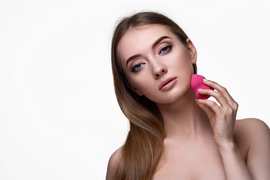 attractive young woman using pink cosmetic sponges isolated on white background