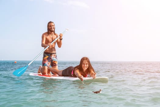 Silhouette of woman standing, surfing on SUP board, confident paddling through water surface. Idyllic sunset or sunrise. Sports active lifestyle at sea or river.