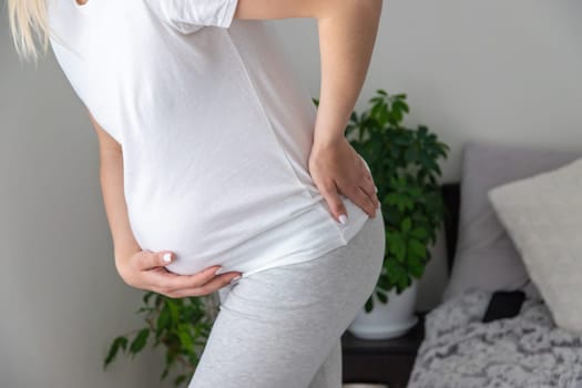 Pregnant woman hurts her back. Selective focus. Home.