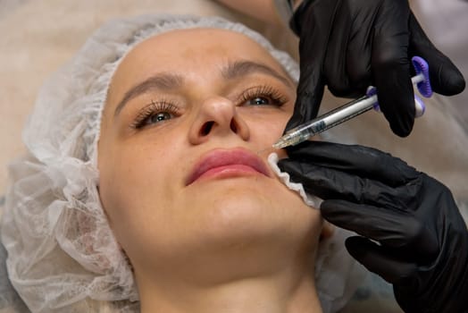 Beauty injections. Young woman receiving a injection in her lips. Selective focus.