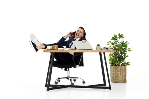 Successful happy businessman working with laptop and having phone conversation with client