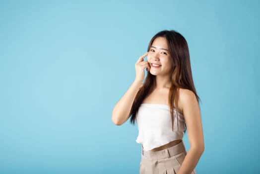 Beauty and Skin care. Asian woman with beauty face touching healthy facial clean skin studio shot isolated on blue background, Beautiful female model smiling with natural makeup and healthy face