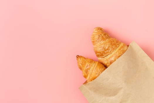 Delicious croissants in a package on a pink background. french pastries. copy space.