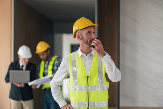 Portrait of male engineer holding walkie talkie and male engineer female with working together inspection housing estate project at the construction site.