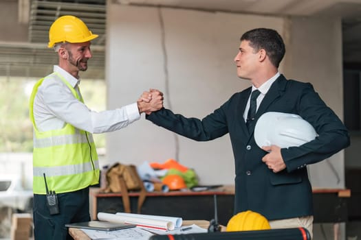 Happy young civil engineer manager and architects handshaking at construction site and looking to next construction phase , cooperation teamwork concept.