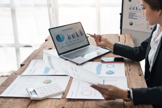 Asian business woman sit at their desks at office and calculate financial graphs showing results about their investments, plan a successful business growth process, diagrams on screen.