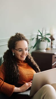 Young woman enjoying online shopping and elearning on laptop at home. Home shopping and elearning with a happy woman using laptop on sofa