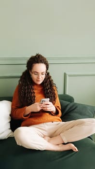 Happy Woman Relaxing on Sofa Using Cell Phone for Shopping and Social Media at Home - Ecommerce and Social Media Concept.